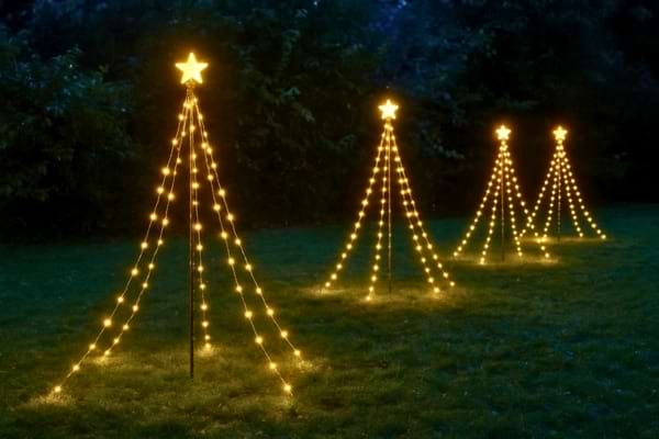 plusieurs sapins lumineux LIDL alignés dans un jardin de nuit, ambiance magique et féérique.