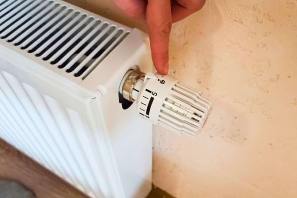 Doigt tournant le bouton d’un radiateur pour régler la chaleur.