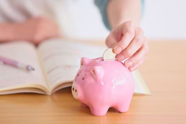 Femme qui met une pièce dans une tirelire.