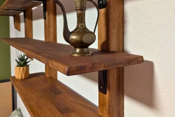 Des étagères en bois décorées d’objets et de plantes sont accrochées à un mur.