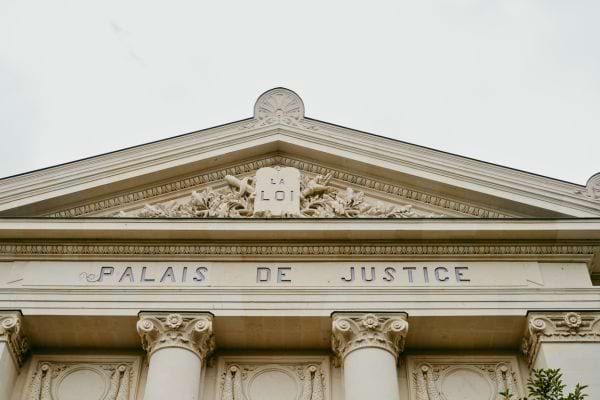 La façade d’un palais de justice avec l’inscription « Palais de Justice » gravée dans la pierre.