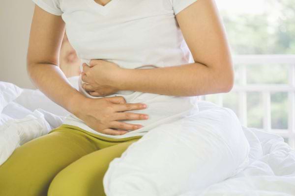 Une patiente garde les mains jointes sur son ventre.