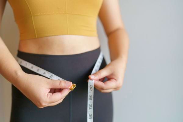 Femme mesurant son tour de taille avec un mètre ruban.