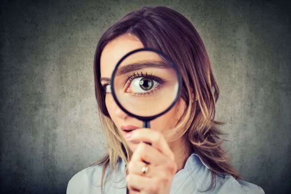 Une femme qui regarde à travers une loupe.