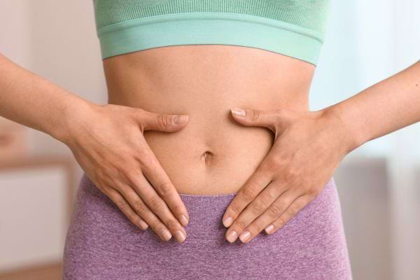 Femme posant ses mains sur son ventre, symbole de digestion ou bien-être abdominal.