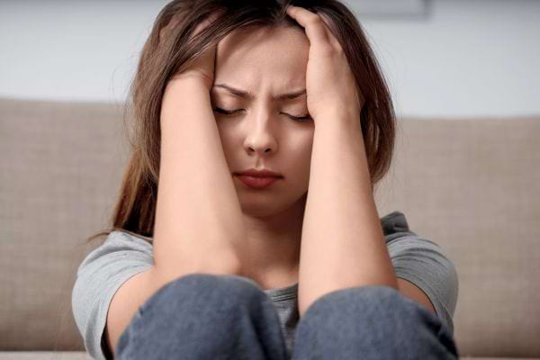 Une jeune femme se tient la tête entre les mains, visiblement bouleversée.