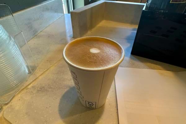 Un café chaud dans un gobelet en carton sur un comptoir.