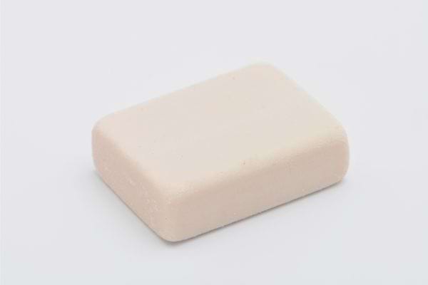 Pain de savon solide blanc posé sur fond clair, symbole d’hygiène naturelle.