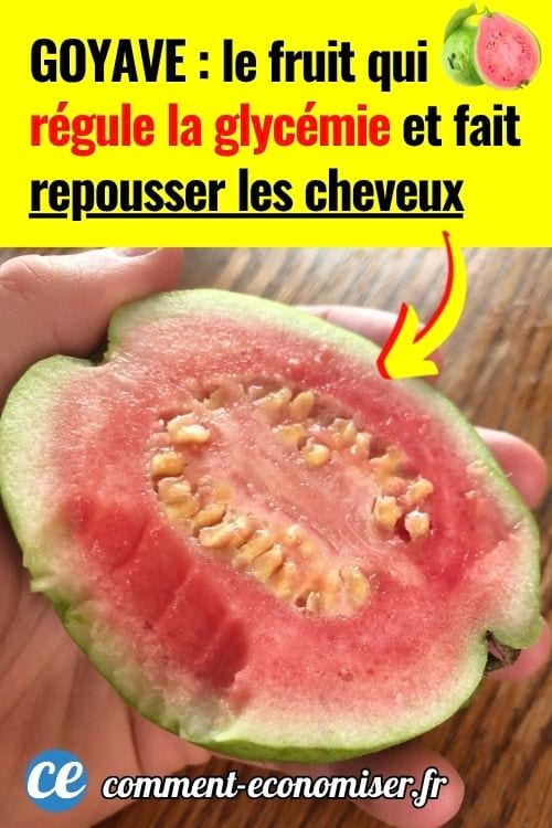 Une main qui tient une moitié de goyave rose.