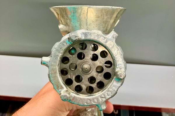 Vue avant d’un hachoir ancien montrant la grille de sortie.