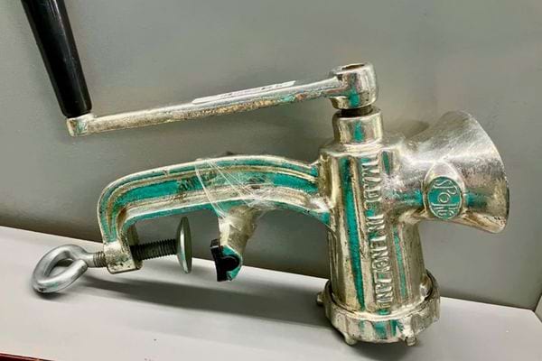 Hachoir à viande en métal poli marqué “made in england”.