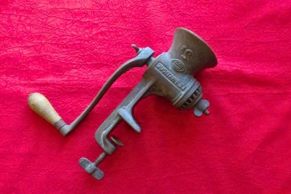 Hachoir à viande ancien noir sur fond rouge.