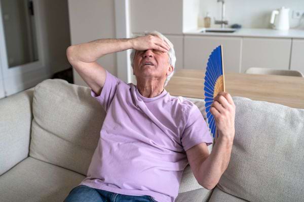 Un homme fatigué tente de supporter la chaleur dans son salon.