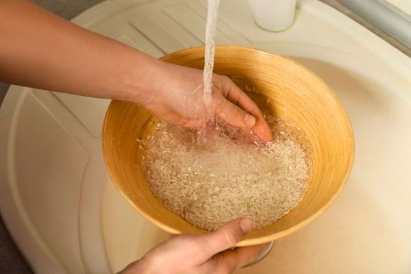 Des mains lavent du riz cru sous l’eau claire.