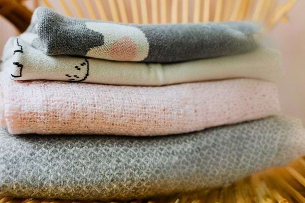 Des vêtements de bébé pliés soigneusement sur une chaise.