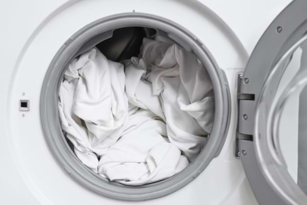 Du linge blanc propre est visible dans le tambour d’une machine à laver.