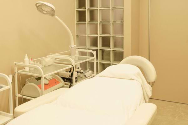 Un lit médicalisé recouvert d’un drap blanc dans une salle de soins.