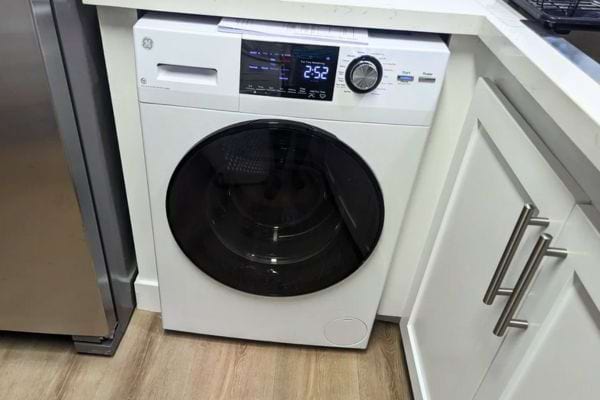 Machine à laver blanche installée dans une cuisine moderne.