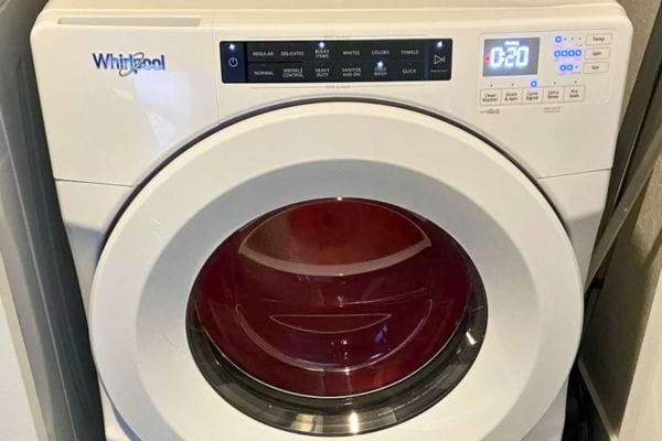 Machine à laver blanche moderne avec hublot rouge et affichage numérique.