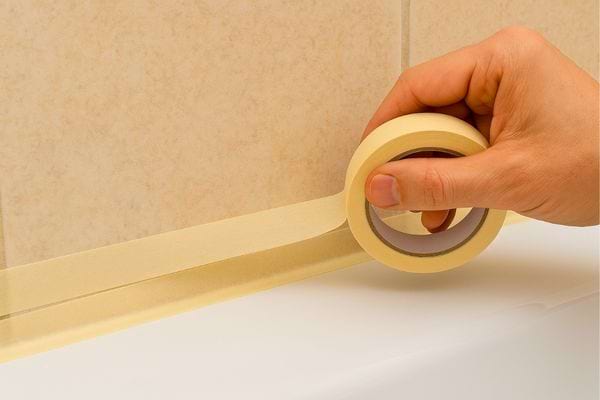 Main pose du ruban de masquage avant d’appliquer le joint.