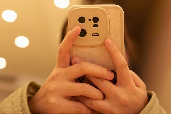 Une personne tient un smartphone à coque beige en bois.