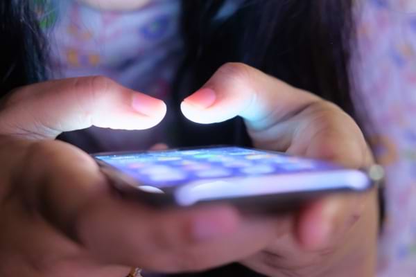 Une personne tient un téléphone éclairé dans le noir.