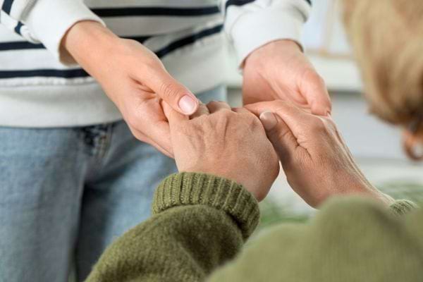 Gros plan sur deux personnes se tenant les mains en signe de soutien.