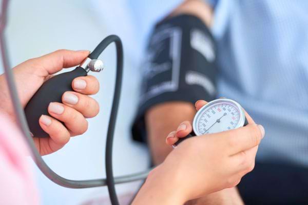 Un professionnel de santé mesure la tension artérielle d’un patient à l’aide d’un tensiomètre manuel.