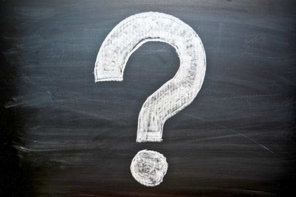 Un grand point d’interrogation blanc dessiné à la craie sur un tableau noir.