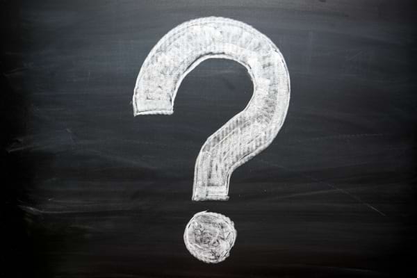 Un grand point d’interrogation blanc est dessiné à la craie sur un tableau noir.