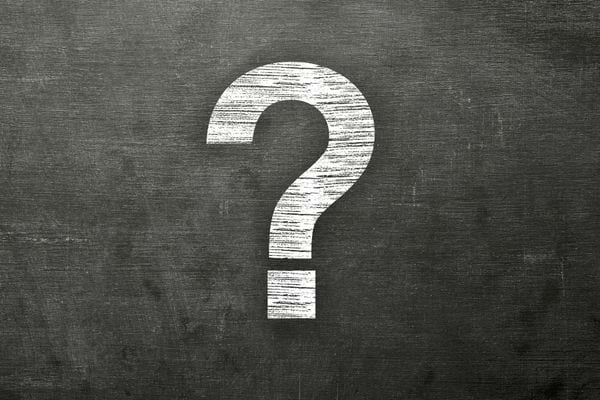 Un grand point d’interrogation blanc est dessiné à la craie sur un tableau noir.