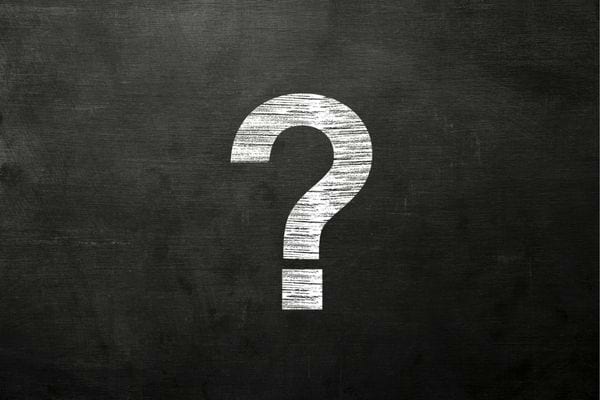 Un grand point d’interrogation blanc tracé à la craie sur un tableau noir.