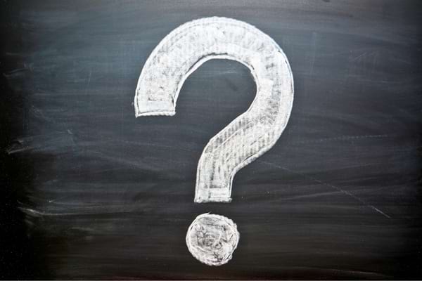 Grand point d’interrogation blanc dessiné à la craie sur un tableau noir.