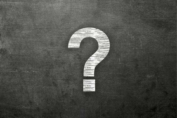 Point d’interrogation blanc dessiné à la craie sur un tableau noir.