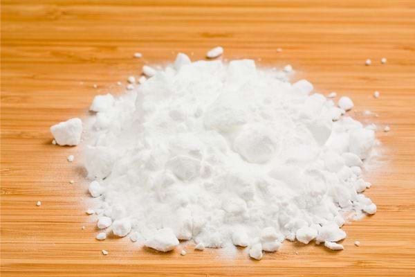 Un tas de poudre blanche éparpillée sur une surface en bois clair.