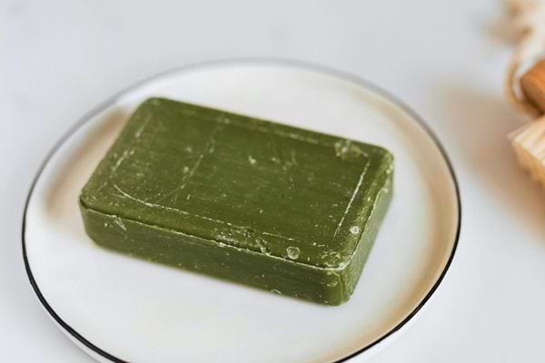 Savon solide vert posé sur une assiette blanche en céramique.