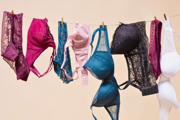Plusieurs soutiens-gorge colorés et en dentelle sont suspendus à une corde, prêts à sécher.