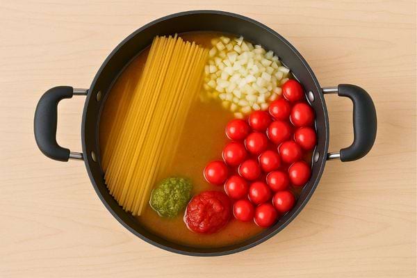 Pâtes crues, tomates, oignons, pesto et bouillon prêts à cuire ensemble.