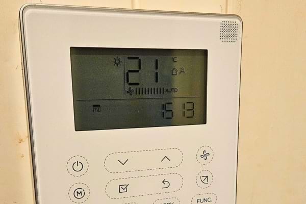 Thermostat numérique affichant 21 degrés, avec boutons et écran rétroéclairé.