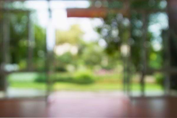 Image floue d’un intérieur donnant sur un jardin vert et lumineux.
