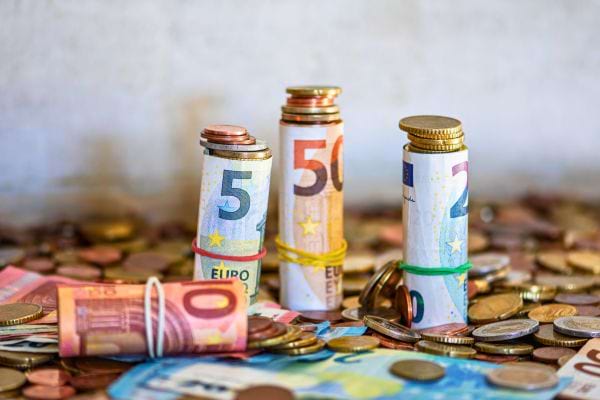 Des billets et pièces d’euros sont éparpillés et rangés par rouleaux.