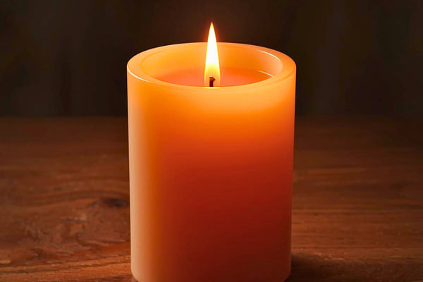 Bougie orange unie allumée sur une table en bois, lumière douce et apaisante.