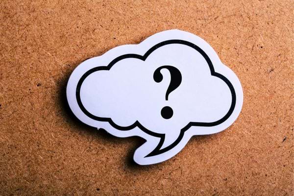 Bulle blanche avec point d&rsquo;interrogation noir sur fond en carton brun.