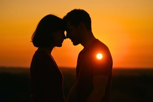 Image poétique de deux silhouettes proches au coucher du soleil