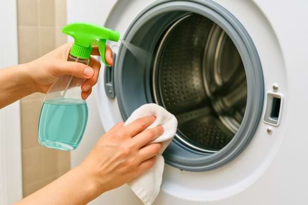 Une femme lavant l'extérieur et les joints d'une machine à laver