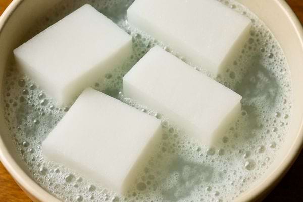 Eponges magiques qui trempent dans une eau savonneuse.