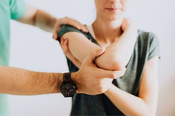 Professionnel de santé examinant le bras d’une femme en consultation.