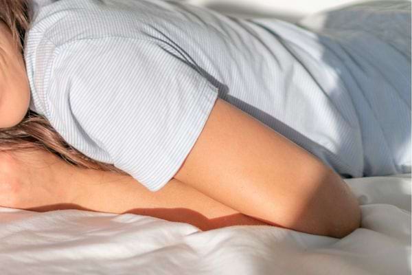 Femme allongée sur le ventre dormant paisiblement dans une lumière matinale douce.