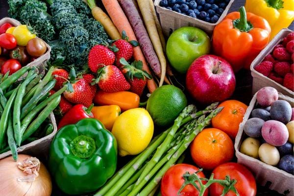 Assortiment de fruits et légumes frais colorés sur une table en bois.