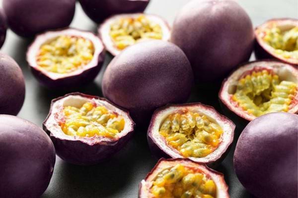 Fruits de la passion violets ouverts montrant leur chair jaune.